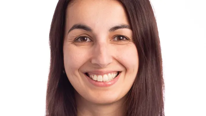 Close up of smiling middle aged woman wearing black turtleneck, posed against a white background