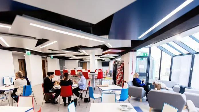 students in large airy cafe style space with large glass windows