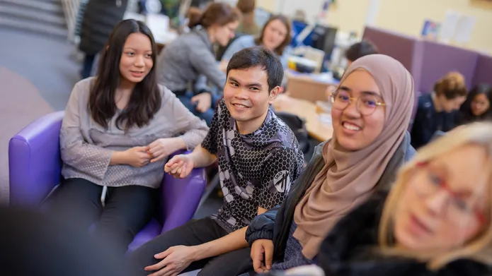 Candid photo of four seated students smiling