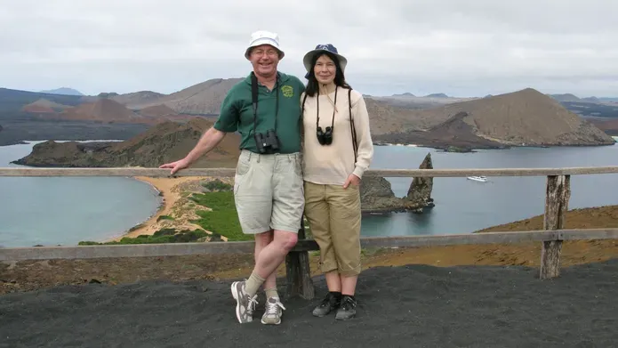 Tricia and Philip stood in front of water and mountain view behind