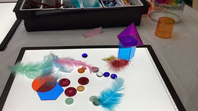 A lightbox with colourful buttons and feathers on top.