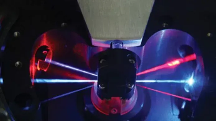 Photograph of 3 laser beams focussed through a lens, with 3 lasers of different colours leaving the lens