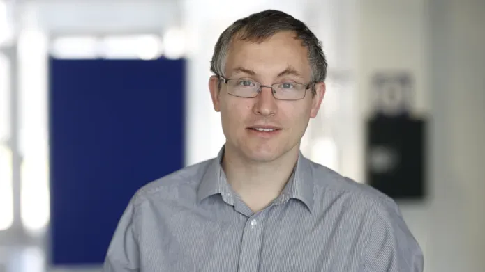 Professor James Chalmers, wearing a grey shirt and glasses in a medical setting