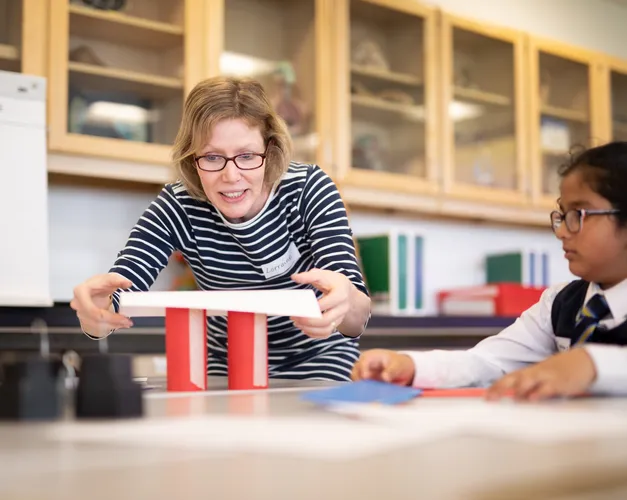 Student showing a primary aged girl how to make a model