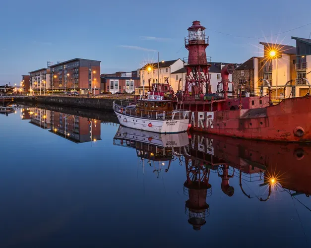 a view of dundee at dusk with the river reflecting the buildings beside it