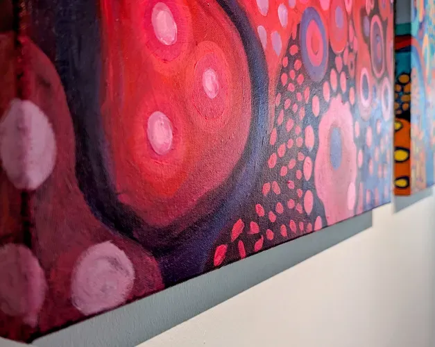 A swirling painting with reds and pinks teases the idea of cellular structures