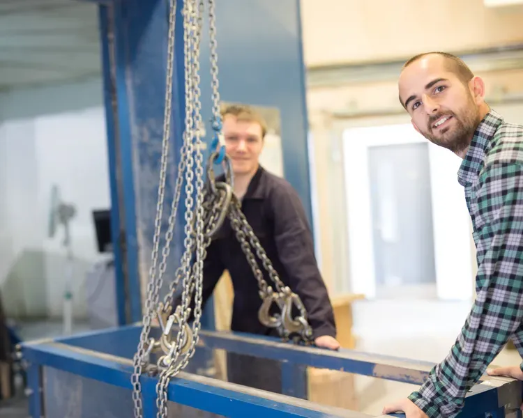 two people lifting something using chains