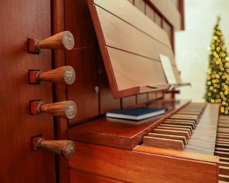 Close up of chaplaincy organ with a Christmas tree in the background