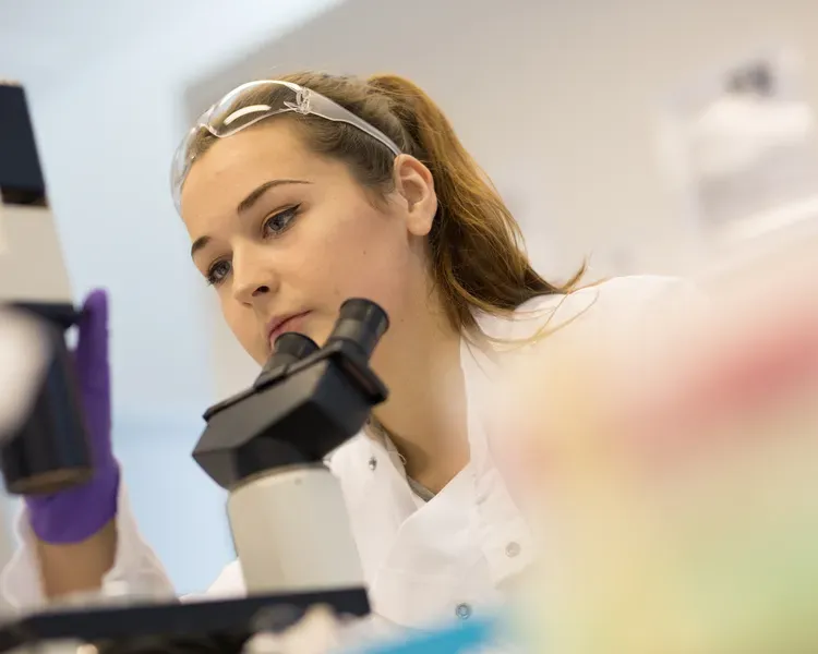 student in lab using a microscope