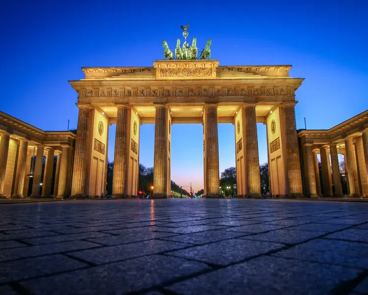 The Brandenburg Gate lit up at sunset, taken from just above the pavement