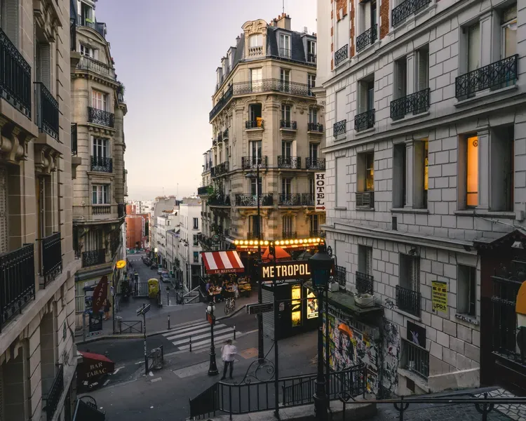 A series of stairs descent between streets of Montmartre in Paris, there are many restaurant and cafe signs in French on the buildings around