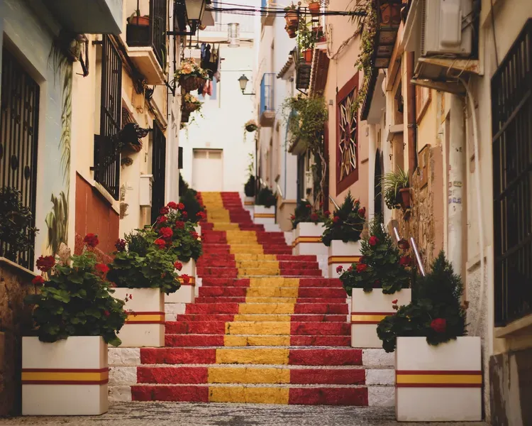 A set of steps painted in the red and yellow colours of the Spanish flag rise through an old town centre.