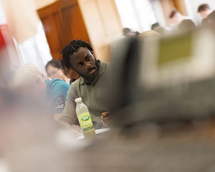 A student looking towards another student sitting in a lecture theatre