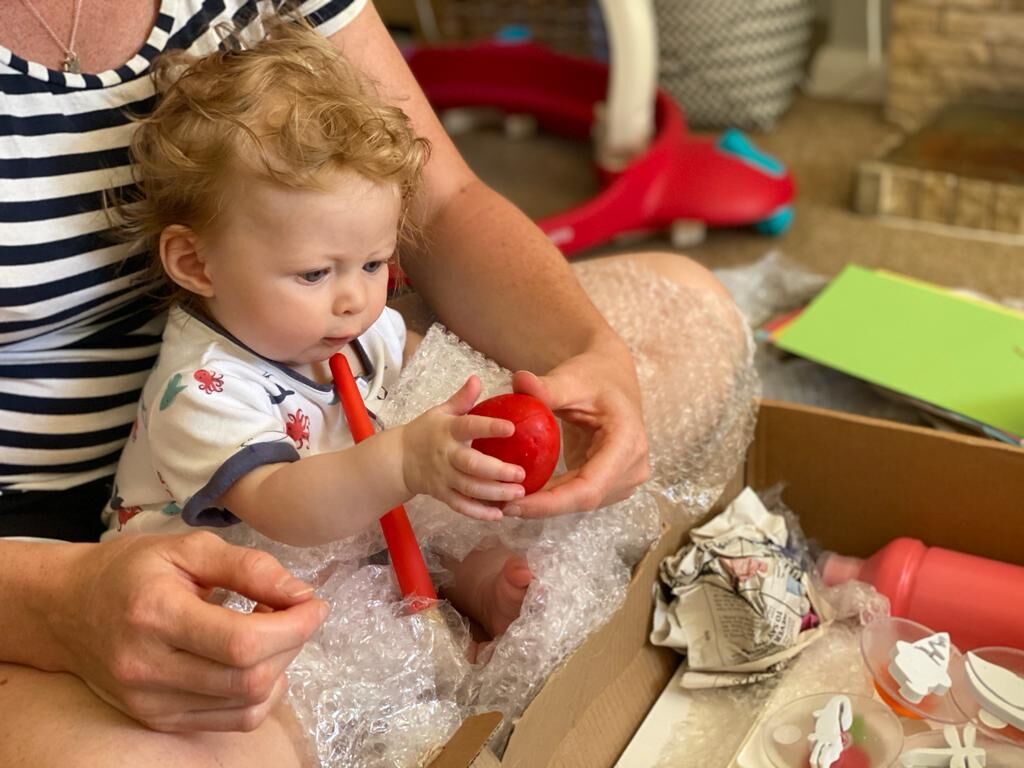 A baby playing with a red ball