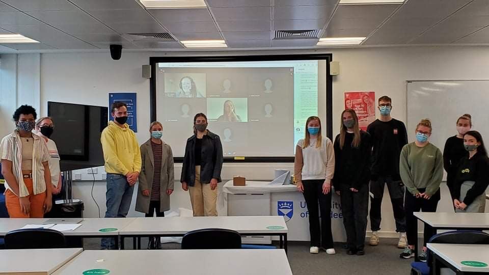 science students standing in front of a projector with Zoom on it, all wearing face masks