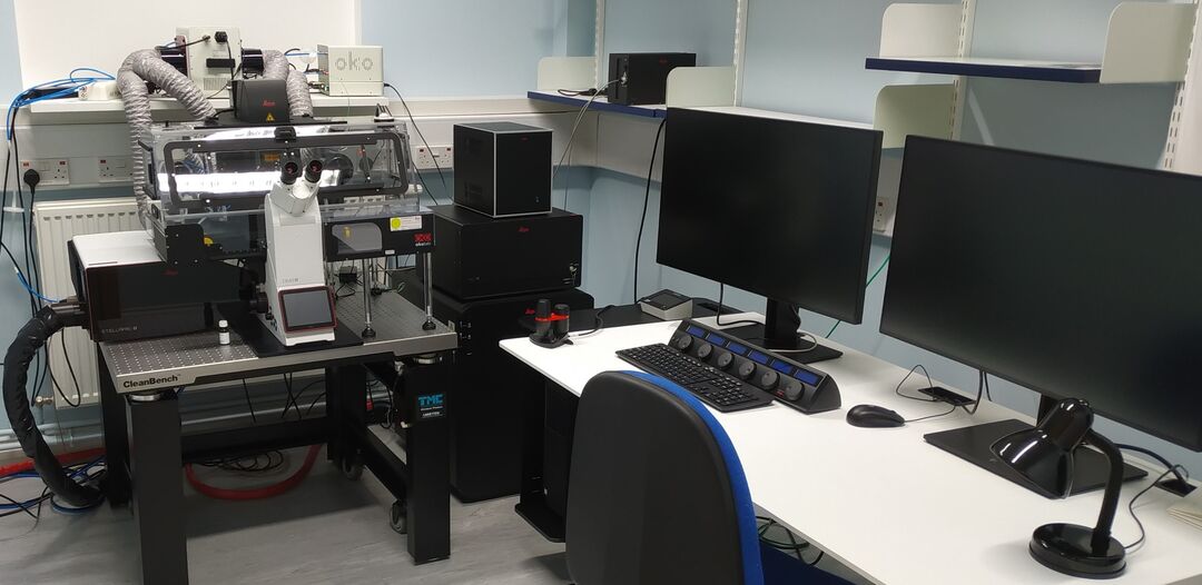large microscope next to two computer screens