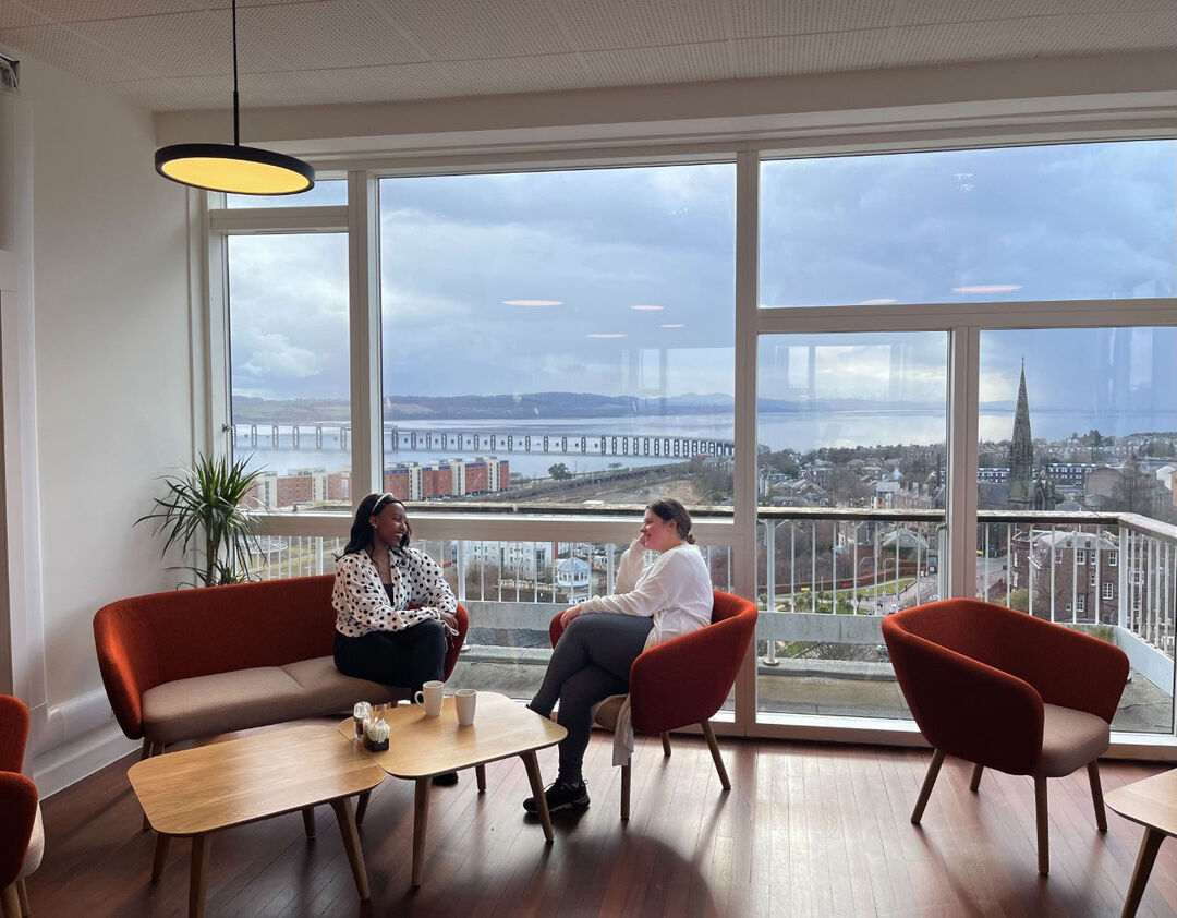Two people sitting at the window of the Tower cafe with views of the River Tay and rail bridge