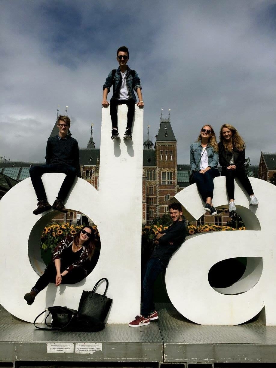 Five people sat on giant sculptures of the letters lowercase d and a