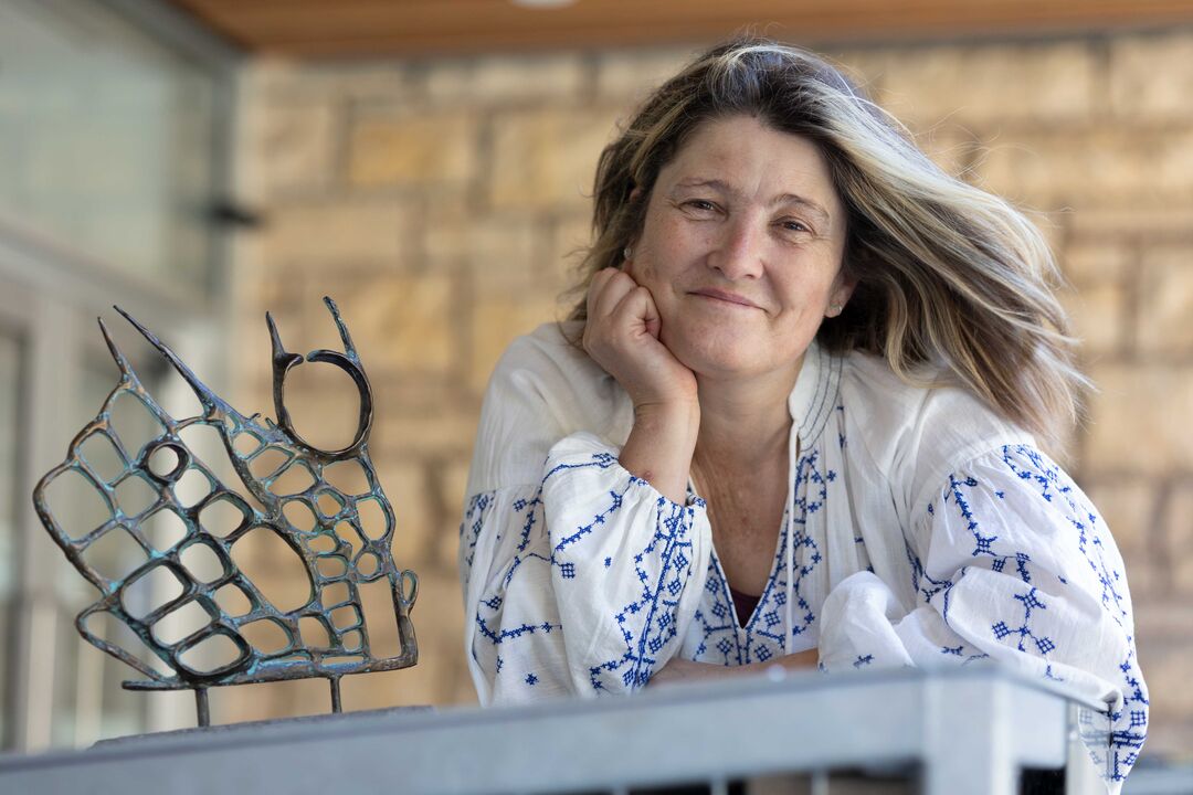 Georgia Crook leans with her head in her hand, with her sculpture beside her.