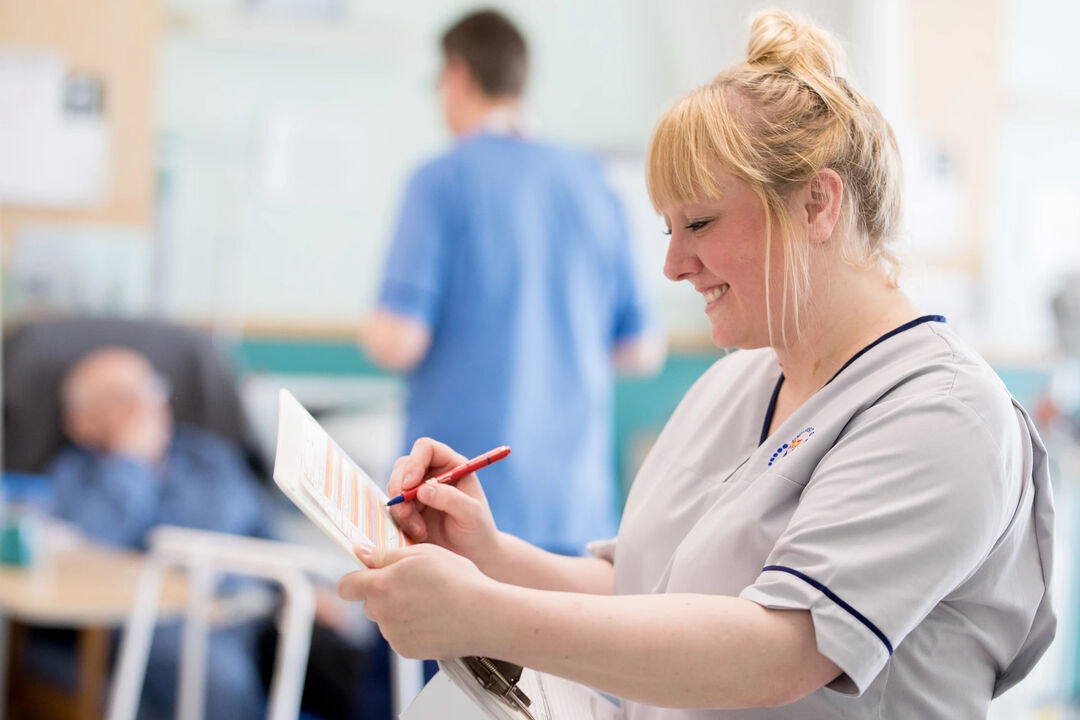 Melanie Love in a hospital ward writing on paper