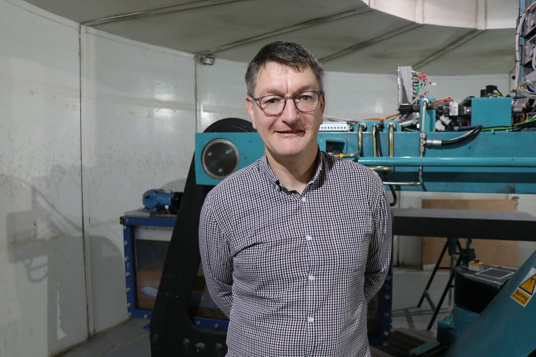 Man wearing checked shirt and glasses standing in front of machinery