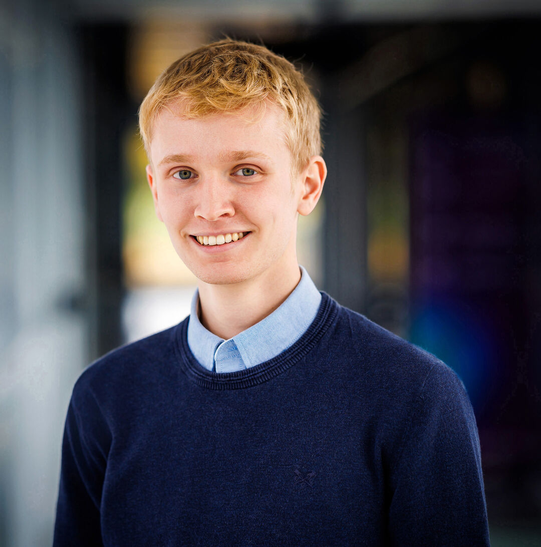 A headshot of student James Wilson, smiling, wearing a navy blue jumper