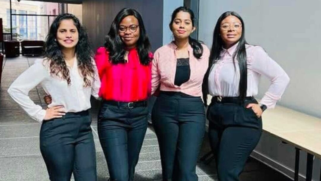 Four girls stand in a line with their arms around each other