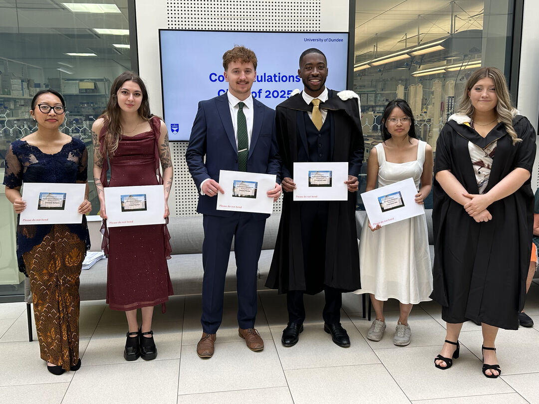 A group of people standing together smiling holding prize certificates
