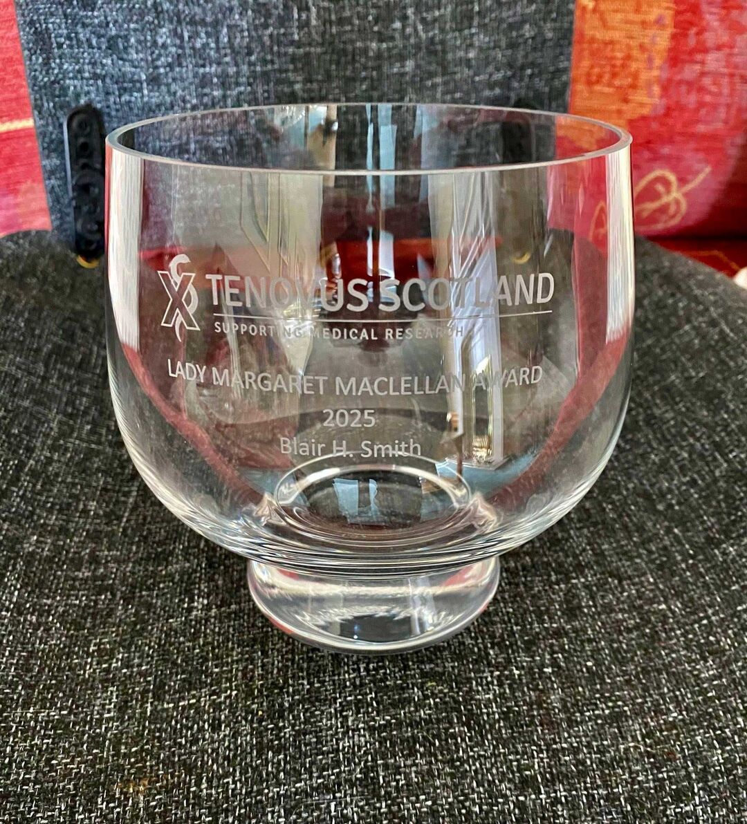 A glass cup award with writing engraved on it.