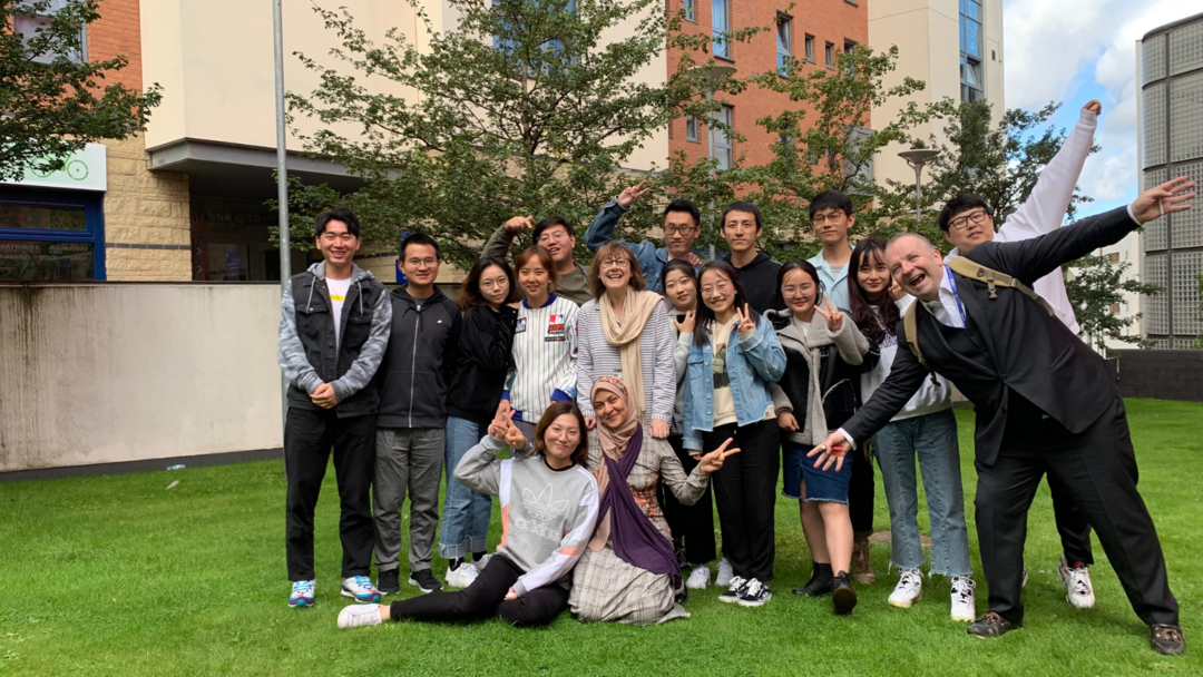 A large group of students smiling and posing at the camera, a mix of students and different ages